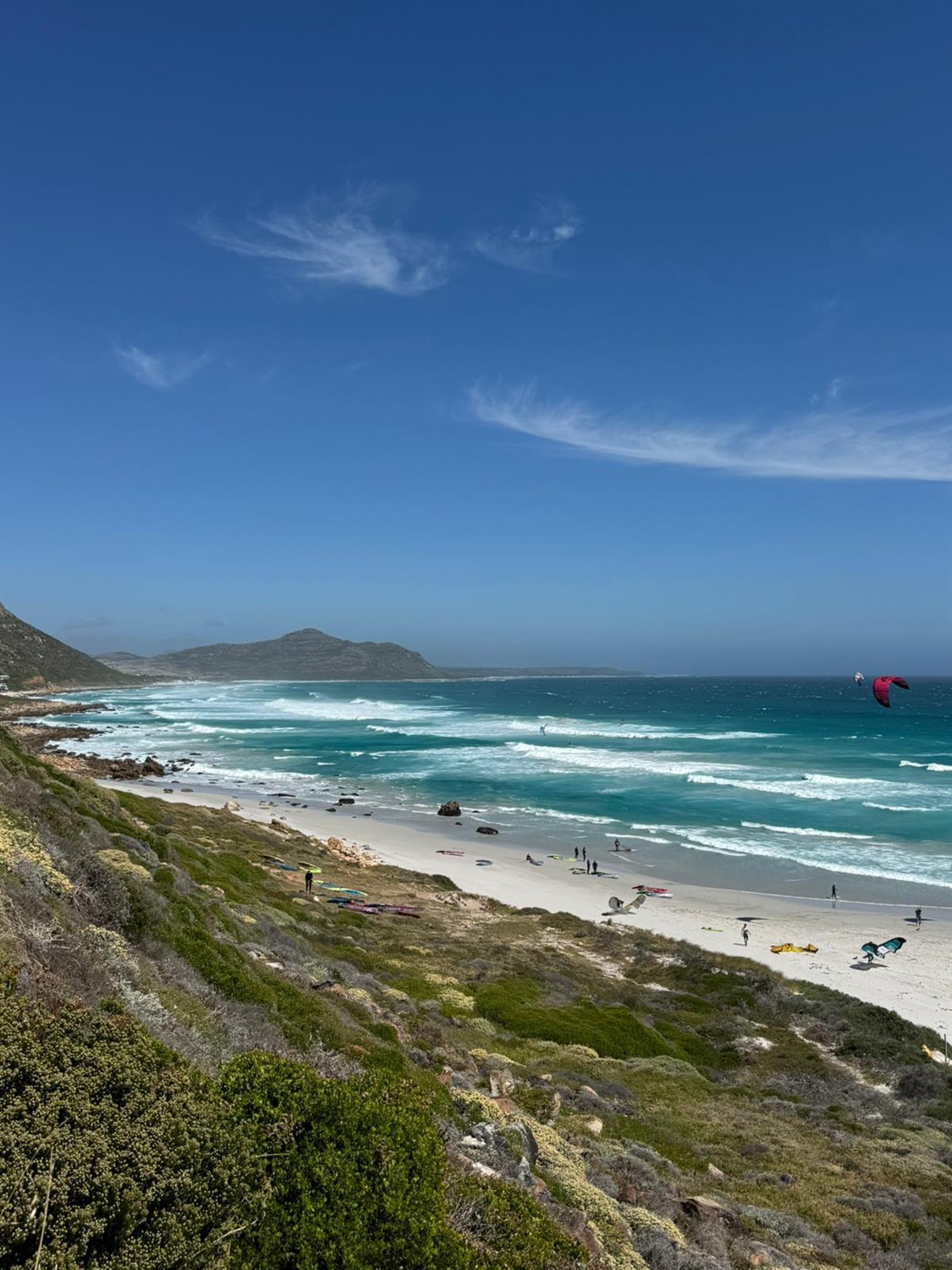 Vue plongeante sur une plage bordée de riders et de vagues