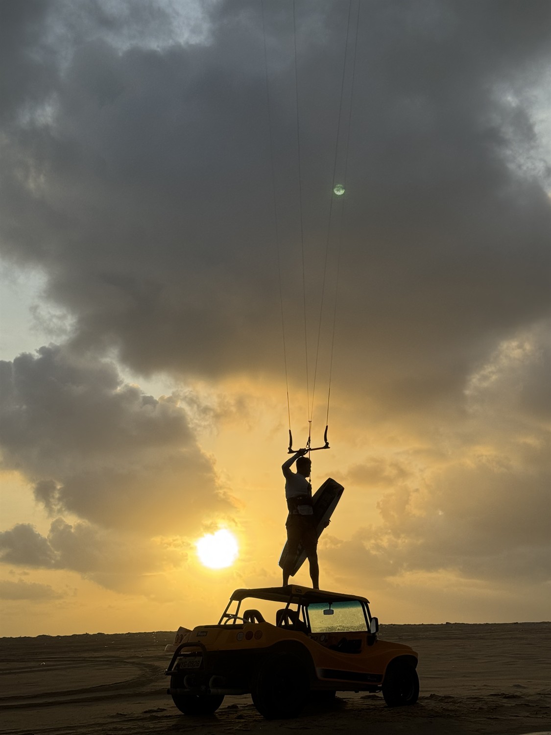 Rider debout sur un buggy au coucher de soleil, kite dans le ciel