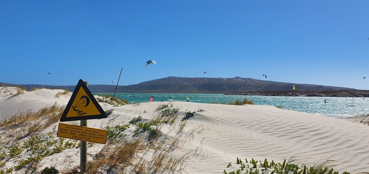 Panneau kitesurf face au lagon rempli de kites