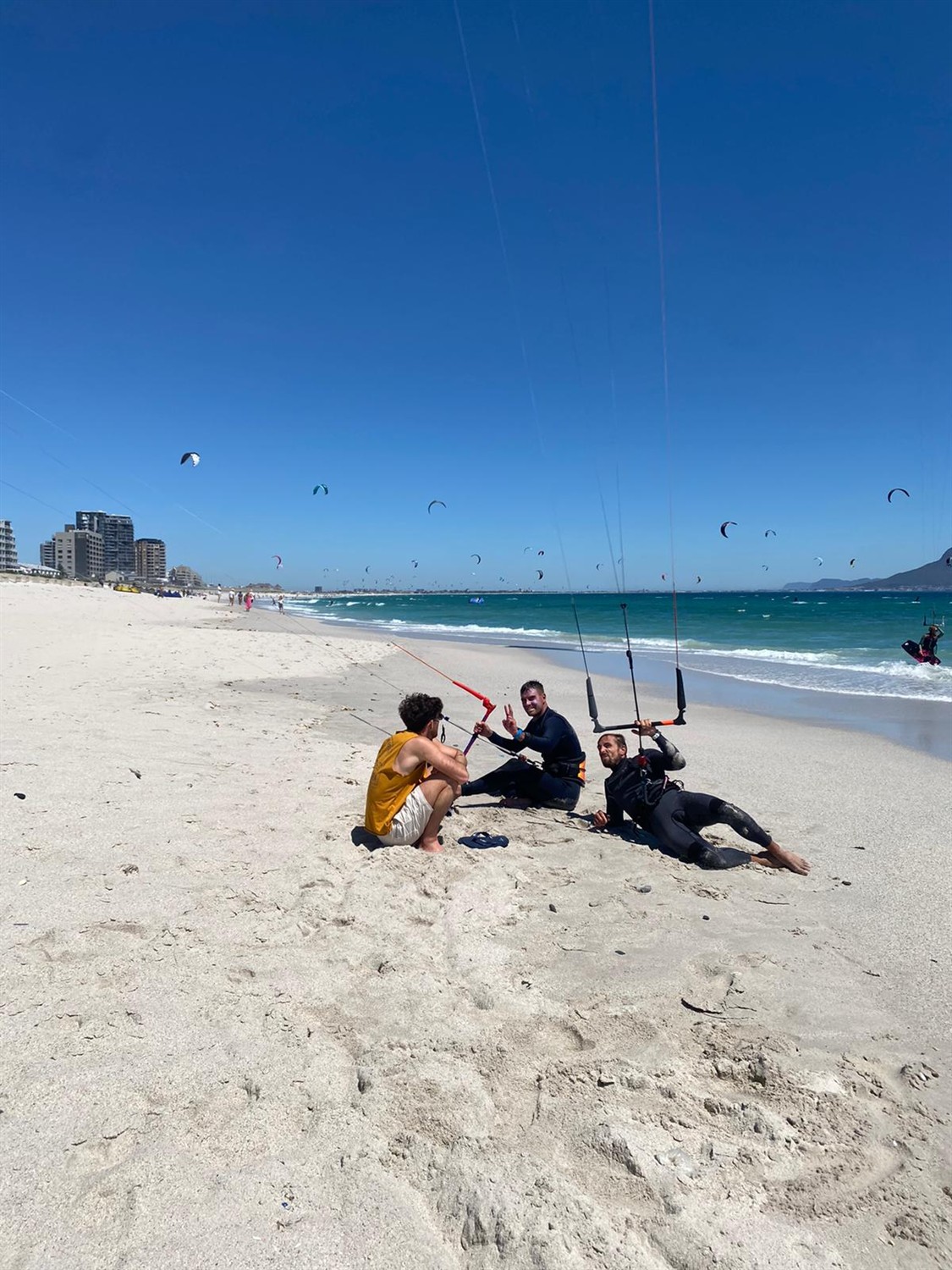 Groupe de riders posant sur le sable, immeubles en arrière-plan