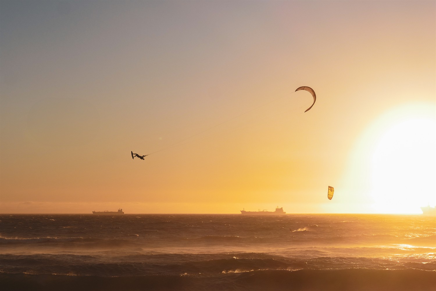 Rider en saut inversé au coucher de soleil, cargos à l'horizon