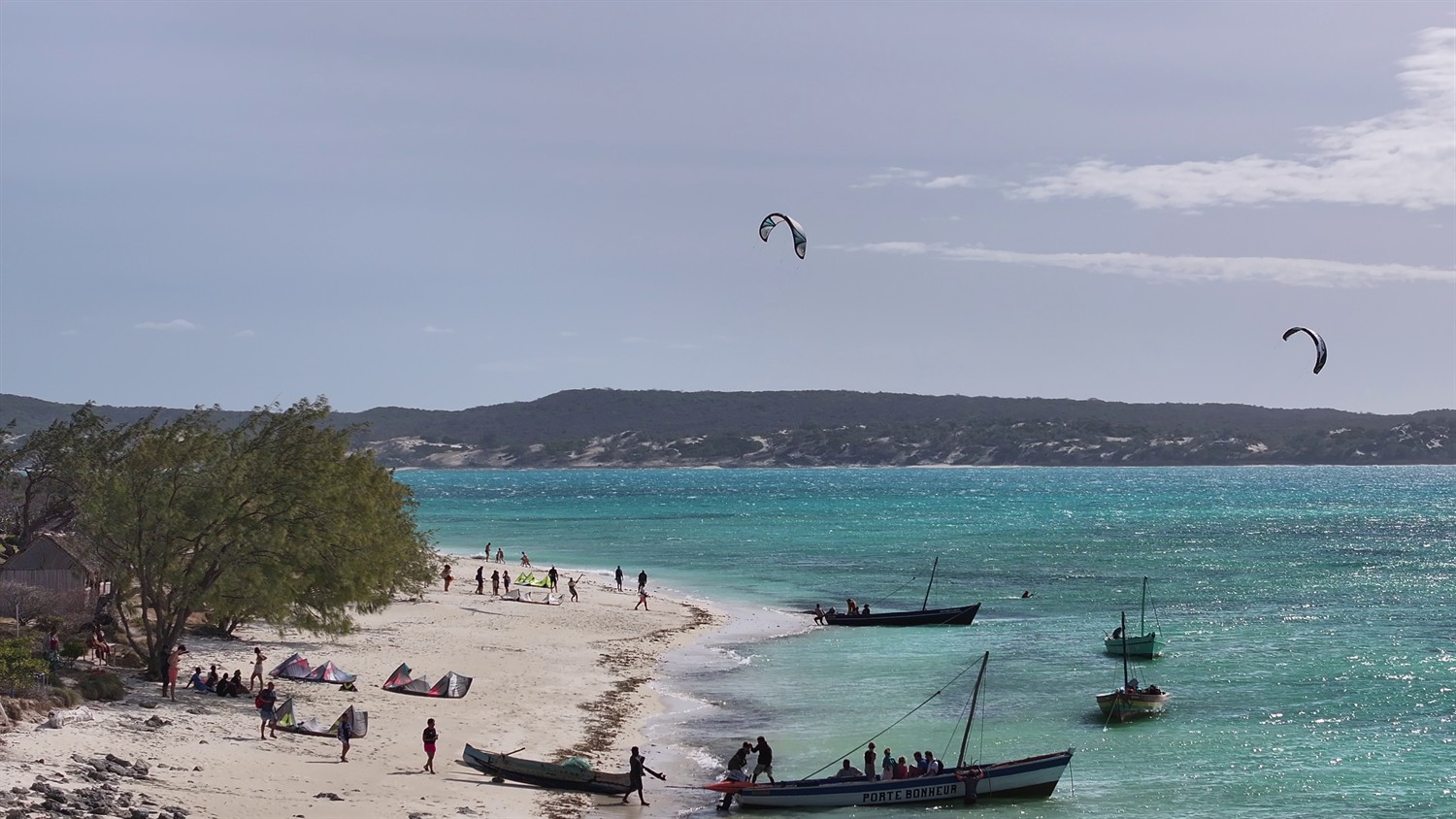 Plage animée avec kites, pirogues et vue sur le lagon